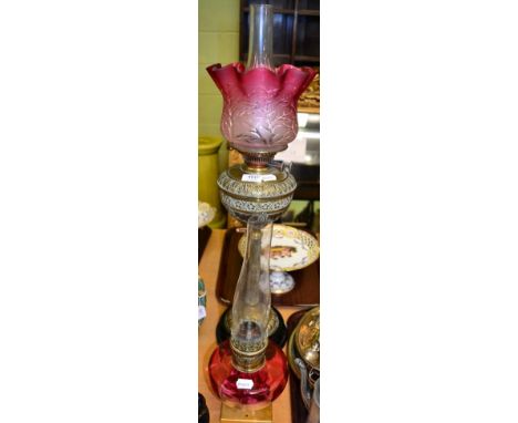 A Victorian brass oil lamp with cranberry shade and a cranberry glass oil lamp reservoir on a later stand (2)