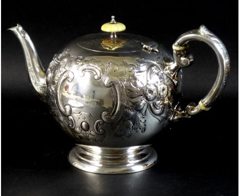 A Victorian silver teapot, of bullet form with scroll handle and foliate clasped spout, decorated with repousse Rococo style 