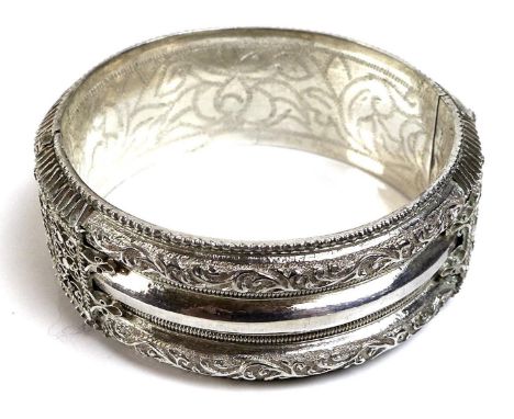 A finely worked broad bangle of Indian style design, the white metal with foliate scrolls, beading and filagree, with engrave