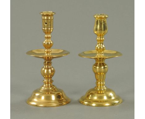 Two Georgian brass candlesticks, with integral drip trays. Height 20 cm. CONDITION REPORT: The candlestick with the tulip sha