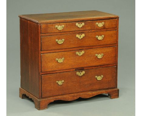 A George III oak chest of drawers, four long graduated drawers with brass drop handles and raised on bracket feet.  Width 82.