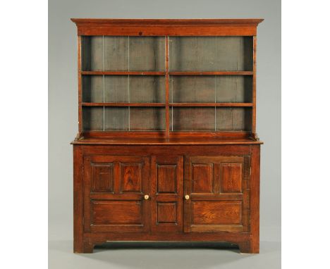 A Georgian oak dresser with Delft rack, the rack with moulded cornice above a series of shelves, the base fitted with panelle