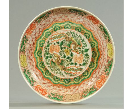A Chinese dished charger, Famille Verte palette decorated with two feng amongst peony within a cloud collar and geometric bor