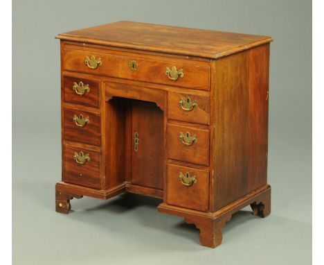 A  George III mahogany kneehole desk, with applied moulded edge above a series of drawers, kneehole and recessed cupboard all