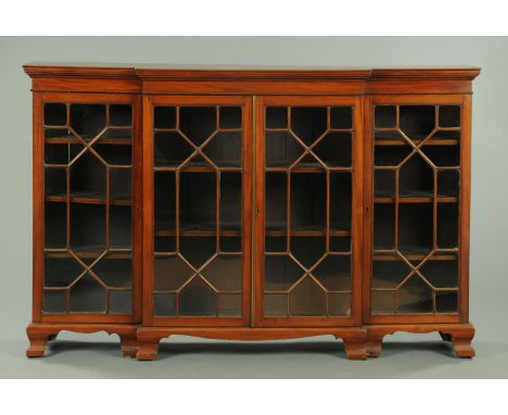 An Edwardian mahogany breakfront low glazed bookcase, with moulded cornice above four glazed doors enclosing adjustable shelv