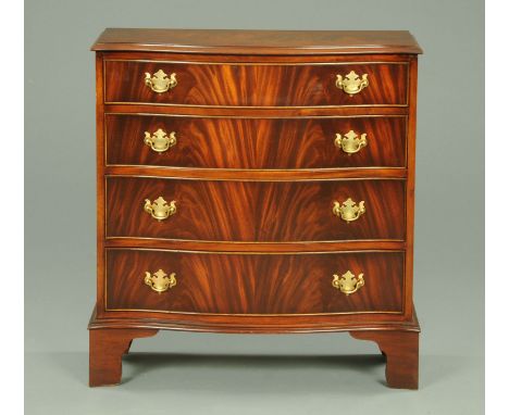 A Reprodux mahogany serpentine fronted chest of drawers, narrow, four drawers with brass drop handles and raised on bracket f
