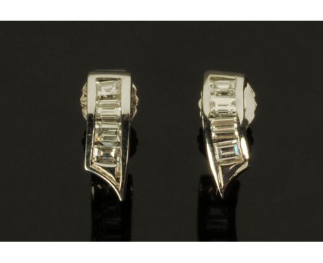 A pair of white metal diamond earrings, each comprising of a curved bar pointed at one end set with four baguette cut diamond