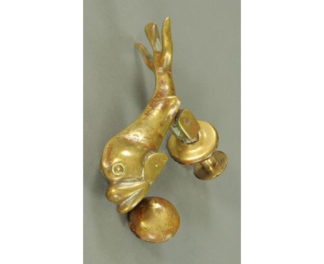 A Victorian brass door knocker, in the form of a dolphin. Length 21 cm.