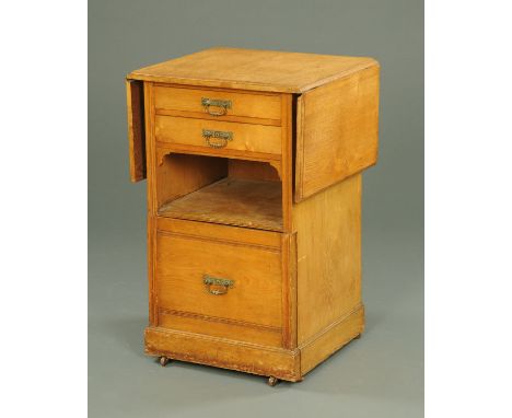 A Shoolbred & Co. oak bedside commode cabinet, twin drop flap and raised on castors.  Width 56 cm. 