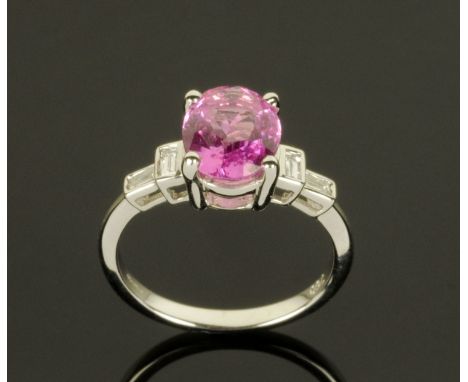 An 18 ct gold oval pink sapphire and baguette diamond shoulder ring, sapphire weight +/- 2.44 carat, size L/M (see illustrati