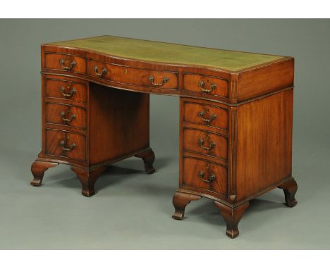 A mahogany serpentine fronted desk, with green tooled leather writing surface and fitted with three frieze drawers and three 