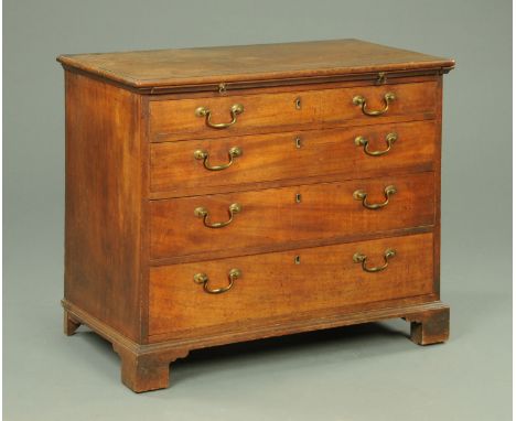 A George III mahogany chest of drawers, with moulded edge, slide and four long graduated drawers with brass drop handles and 