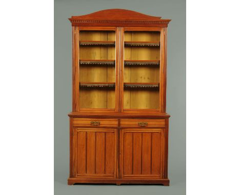 A mahogany bookcase on cupboard, circa 1880, with arched pediment above dentil moulding, with glazed doors enclosing adjustab