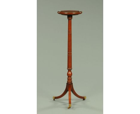 A mahogany torchere, with ring turned column and three downswept legs terminating in brass capped castors.  Diameter 28 cm.  