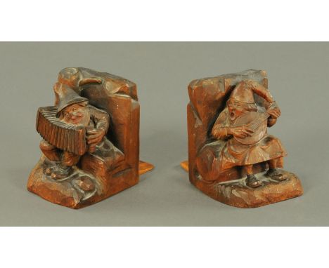 A pair of novelty carved Black Forest bookends, circa 1900, each carved as a humorous figure seated either with an accordion 