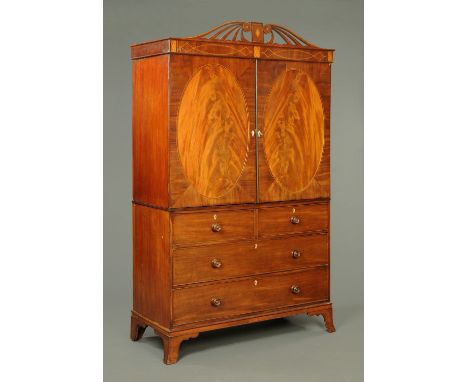 An early 19th century mahogany linen press, with detachable moulded cornice with fretwork pediment above pair of oval panelle