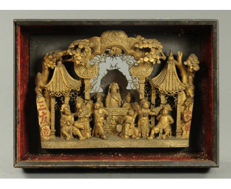 A carved and gilded wood diorama, 19th century, depicting three central figures behind an altar beneath a ruyi shaped canopy,