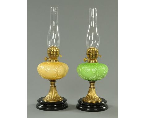 A pair of 19th century lamps, with moulded glass reservoirs and ceramic plinths.  Height 57 cm including chimney.    CONDITIO