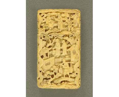 A Canton carved ivory card case, circa 1860, carved with seated and upright figures amongst buildings and pine trees, the sid