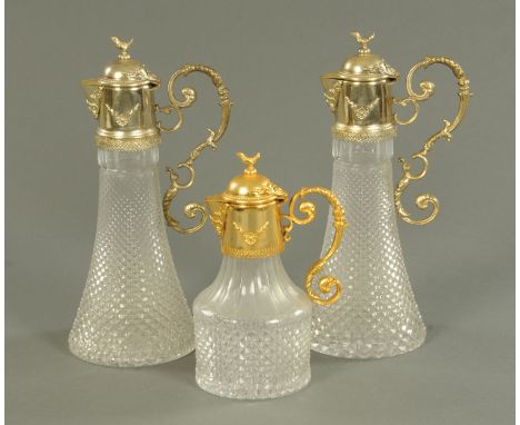 A pair of moulded glass claret jugs, with plated mounts, and a matching spirit decanter with gilt plated mounts, each with bi