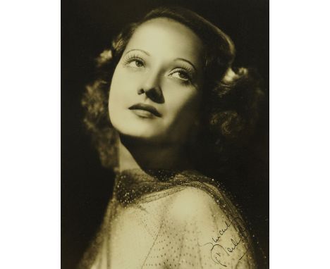 Merle Oberon (1911-1979), a black and white portrait photograph, posed over the shoulder, signed in black ink "sincerely Merl