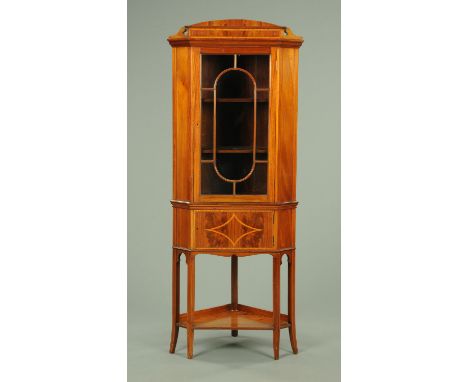 An Edwardian inlaid mahogany corner display cabinet, with shaped pediment, moulded cornice, glazed upper door and panelled lo