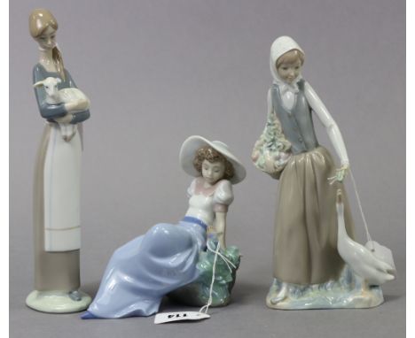 A Lladro Nao porcelain ornament in the form of a seated female figure with a bird by her side, 6¼” high; together with two ot
