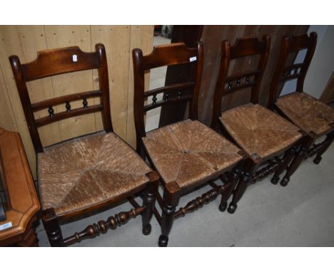 A set of four 19th Century spindle back kitchen chairs having rush seats, having rail and bobbin style backs and turned stret