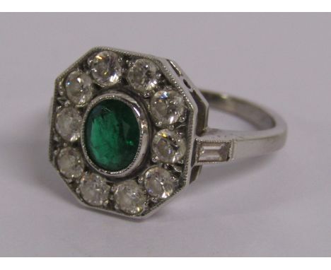 18ct white gold ring with central oval emerald surrounded by round brilliant cut diamonds with each shoulder mounted with bag