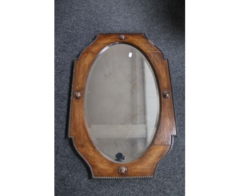 A shaped Edwardian bevelled oak mirror 