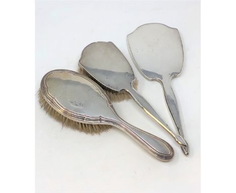 A silver hand mirror, matching brush and another non-matching silver brush. (3)