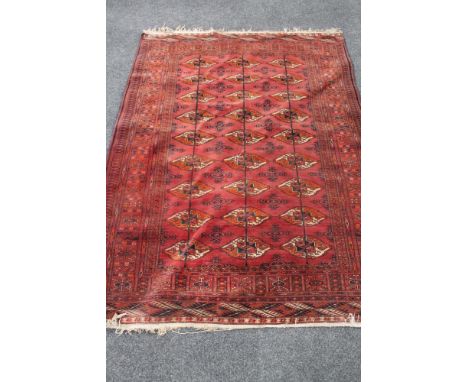 A Bokhara rug, Afghanistan, on red ground  CONDITION REPORT: 193cm by 143cm. Generally in good condition but with one small p