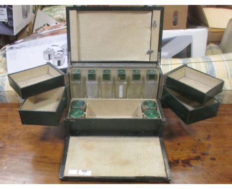 A 1930's green leather dressing case, the interior fitted with ten numbered bottled with green enamel lids  