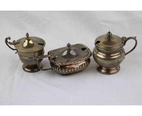 Three unassociated silver mustard pots/ salt cellars, comprising Edwardian example with gadrooning to lower half, ribbed desi