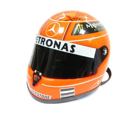 A Shoei motorcycle helmet, in orange, with Bridgestone and Pertronix Mercedes F1 advertising in orange. 