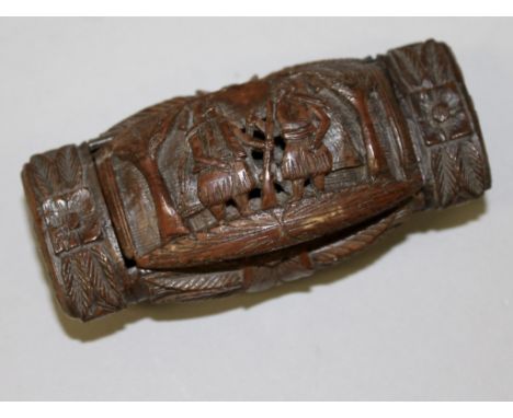 A LARGE CARVED NUT SNUFF BOX carved with figures, palm trees etc.  3.25ins long.