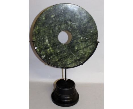 A LARGE CIRCULAR JADE DISC with a hole in the centre.  12ins diameter.