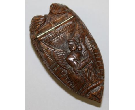 A CARVED NUT SNUFF BOX with lift up lid carved with a figure.  3ins long.