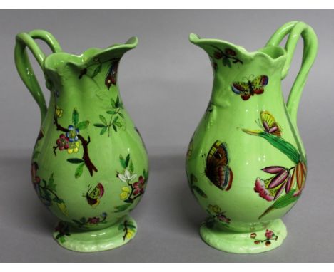 A PAIR OF POSSIBLY SPODE GREEN JUGS with enamel decoration of flowers and butterflies. Mark No. 1076.  6ins high.