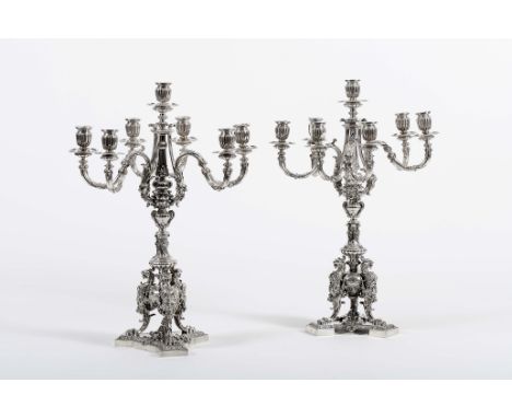 A pair of A three-armed candelabra with seven-light each, 950/1000 silver, decoration en relief "Urns and imaginary animals",