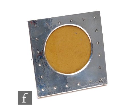 An Edwardian hallmarked silver square easel photograph frame detailed with rivet marks to a planished ground, 15cm square, Sh