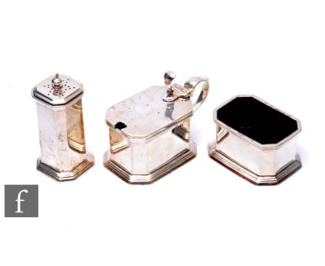 A George V three-piece silver hallmarked cruet, comprising salt, pepperette, and mustard, lacking spoons, with blue glass lin