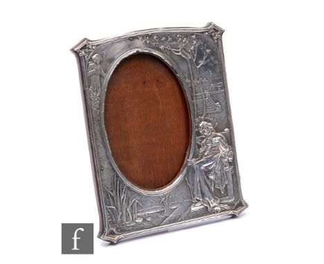 An Edwardian hallmarked silver rectangular easel photograph frame embossed with the study of a seated lady in a landscape set