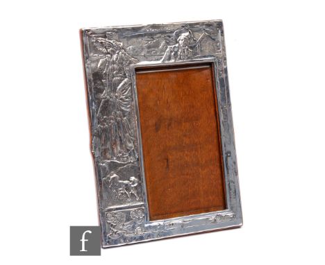 An Edwardian hallmarked silver rectangular easel photograph frame with embossed decoration of a standing woman and a dog to a