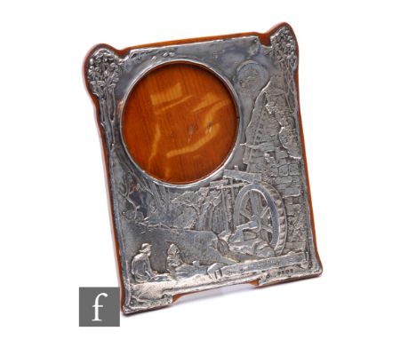 An Edwardian hallmarked silver rectangular easel photograph frame decorated with an embossed landscape scene with two figures