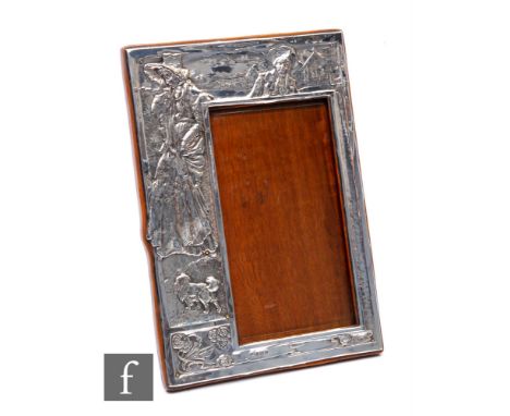 An Edwardian hallmarked silver rectangular easel photograph frame with embossed decoration of a standing woman and a dog to a