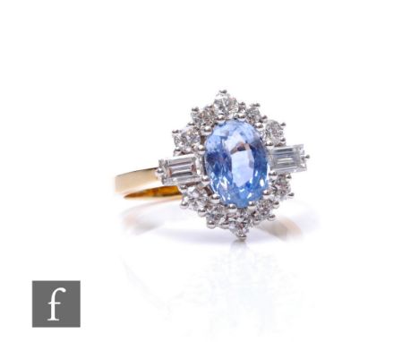 An 18ct sapphire and diamond cluster ring, central oval claw set sapphire flanked by twin baguette diamond to shoulders and t