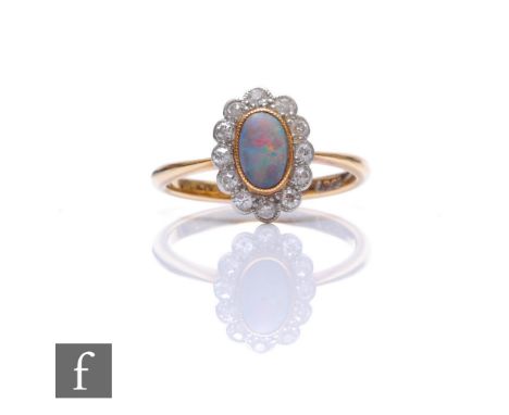 An early 20th Century 18ct opal and diamond cluster ring, central oval cabochon cut opal within a border of twelve diamonds, 