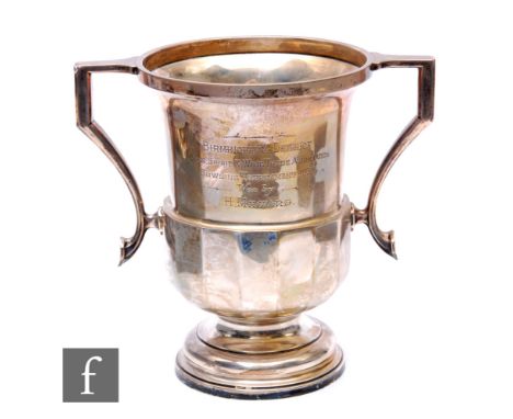 A hallmarked silver twin handled pedestal trophy cup with part panelled decoration below presentation inscription, weight 23.