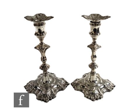 A composed pair of hallmarked silver candlesticks each with shaped square bases below knopped stems and conforming sconces, h